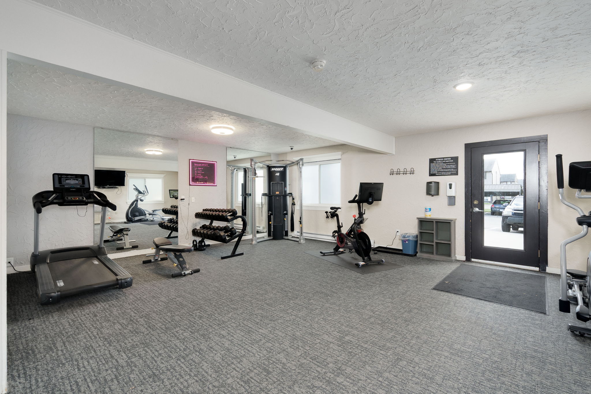 A gym with a variety of equipment including treadmills, weights, and exercise bikes.